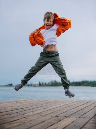 Foto de Niño feliz saltando a la orilla del lago - Imagen libre de derechos