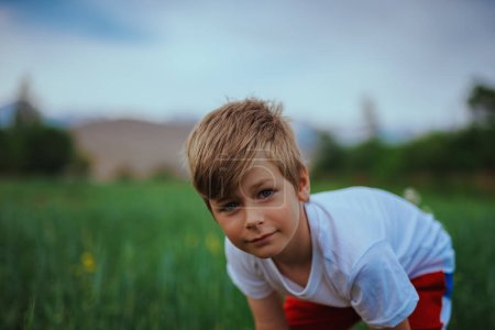 Téléchargez les photos : Portrait de mignon garçon de sept ans dans un champ - en image libre de droit