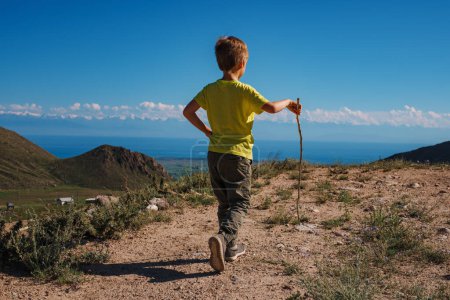 Foto de Chico excursionista con palo camina en un sendero de montaña - Imagen libre de derechos