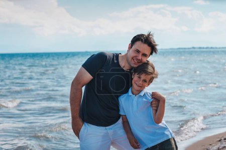 Foto de Feliz padre e hijo de pie en la orilla del lago en un día soleado de verano - Imagen libre de derechos
