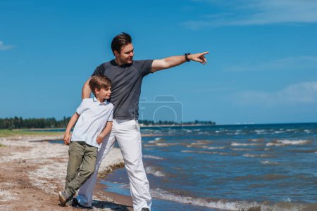 Foto de Padre e hijo de pie en la orilla del lago y mirando hacia otro lado - Imagen libre de derechos