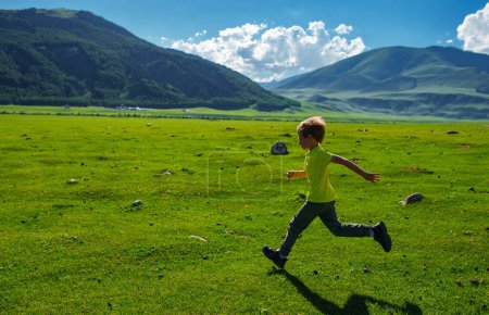 Photo for Boy running fast on a green meadow in the mountains - Royalty Free Image