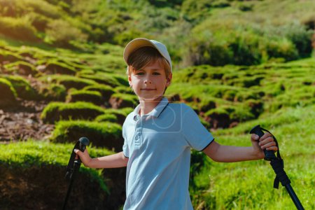 Téléchargez les photos : Garçon randonneur avec bâtons de trekking portrait dans les montagnes - en image libre de droit