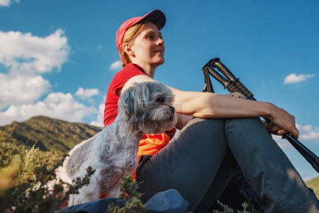 Photo for Young woman hiker with shih tzu dog sitting on top of the mountain, focus on dog - Royalty Free Image