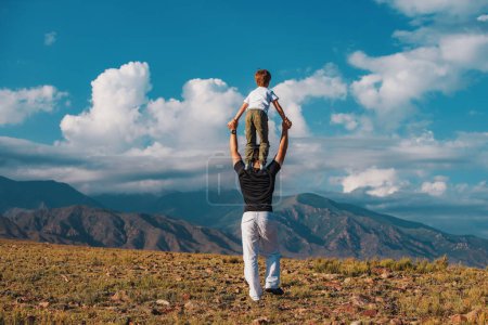 Photo for Boy standing on his father's shoulders on mountains background - Royalty Free Image