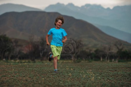 Téléchargez les photos : Joyeux garçon courir sur fond de montagnes - en image libre de droit
