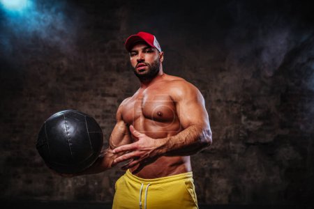 Photo for Athletic muscular man holding heavy fitness ball for workouts - Royalty Free Image