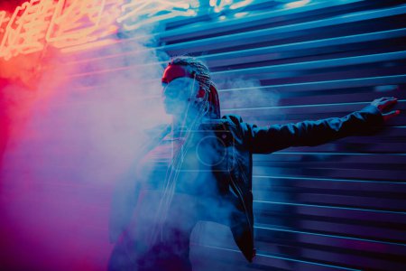 Téléchargez les photos : Jeune femme posant dans la rue avec des néons et de la fumée la nuit - en image libre de droit