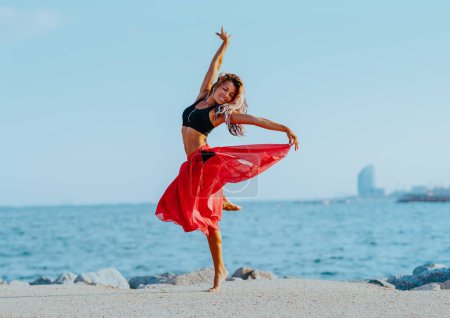 Foto de Joven hermosa mujer bailando en la playa - Imagen libre de derechos