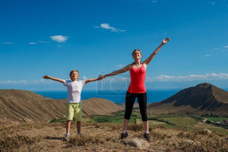 Photo for Happy mom and son stretching at the top of the mountain - Royalty Free Image