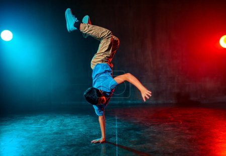 Photo for Boy breakdancing in dark studio with lights - Royalty Free Image
