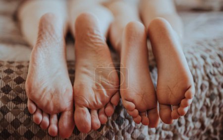 Photo for Feet of the mother and baby lying on the bed - Royalty Free Image