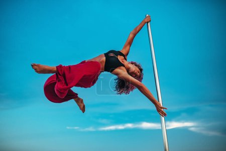 Téléchargez les photos : Jeune belle femme pole dance sur fond de ciel - en image libre de droit