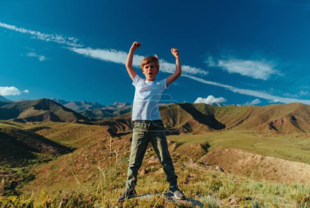 Foto de Niño feliz en el día de verano de pie en las montañas en una pose heroica - Imagen libre de derechos