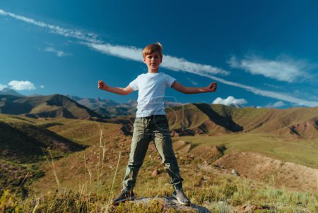 Foto de Niño feliz en el día de verano de pie en las montañas en una pose heroica - Imagen libre de derechos