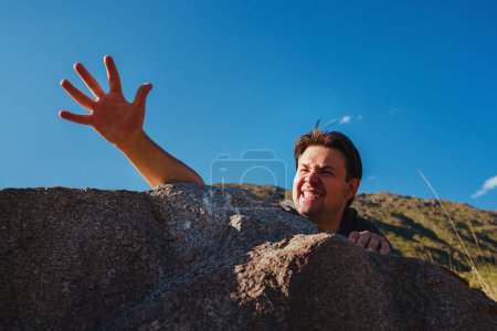 Photo for Young man tourist falling from high mountain and trying to climb up - Royalty Free Image