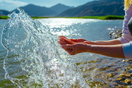 Téléchargez les photos : Femme mains avec des éclaboussures d'eau propre au bord de la rivière des montagnes - en image libre de droit