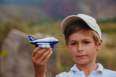 Téléchargez les photos : Garçon en casquette tenant jouet avion, concept de voyage aérien, se concentrer sur l'avion - en image libre de droit