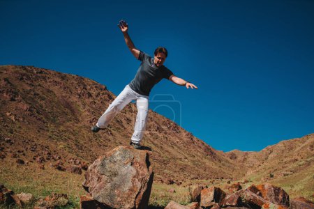Photo for Young man falling from big stone in the mountains - Royalty Free Image