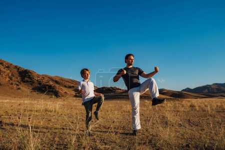 Téléchargez les photos : Père et fils faisant des exercices sportifs sur fond de montagne - en image libre de droit