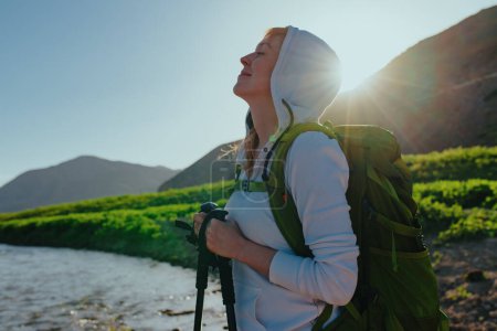 Foto de Mujer feliz excursionista con los ojos cerrados disfrutando de la naturaleza a la luz del atardecer - Imagen libre de derechos