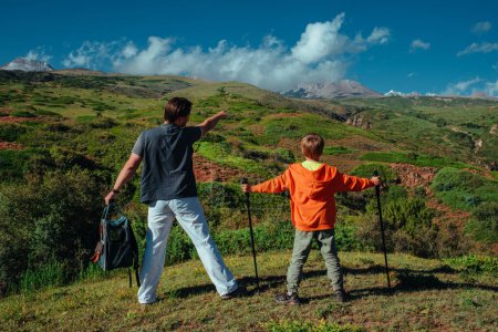 Téléchargez les photos : Père montre à son fils quelque chose au loin debout sur la montagne - en image libre de droit