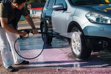 Téléchargez les photos : Homme laver sa voiture en libre-service station de lavage de voiture le jour de l'été - en image libre de droit