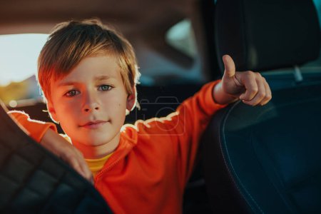 Photo for Cute blond boy in automobile interior showing thumbs up - Royalty Free Image
