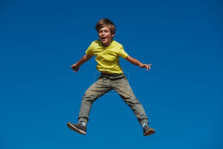 Téléchargez les photos : Joyeux garçon sautant sur fond de ciel bleu - en image libre de droit