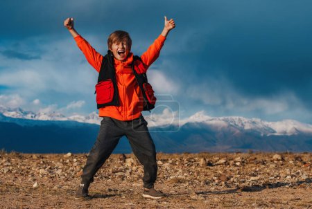 Foto de Feliz turista chico emocional en el fondo de las montañas en otoño - Imagen libre de derechos
