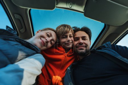 Téléchargez les photos : Parents heureux avec leur fils posant dans l'intérieur de la voiture - en image libre de droit