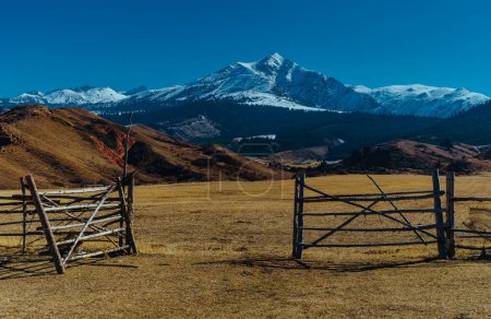 Téléchargez les photos : Zone de pâturage avec clôture en bois sur fond de montagnes - en image libre de droit