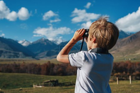 Foto de Niño con prismáticos en las montañas mirando a la distancia - Imagen libre de derechos