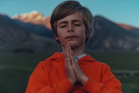 Téléchargez les photos : Portrait de garçon avec bras croisés sur fond de montagne, concept de méditation - en image libre de droit