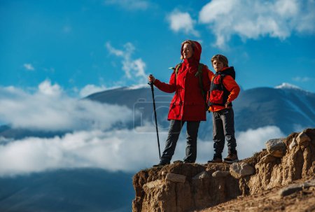 Téléchargez les photos : Jeune femme touriste avec son fils debout au sommet de la montagne et regardant loin - en image libre de droit