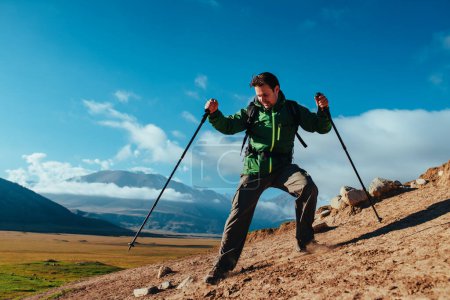 Foto de Hombre excursionista con bastones de trekking bajando de las rocas - Imagen libre de derechos