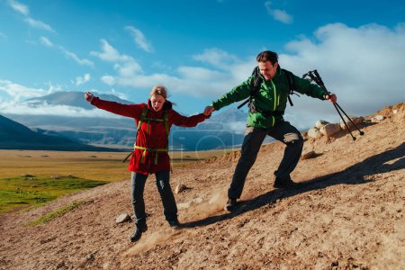 Foto de Hombre y mujer excursionistas bajando de la roca en el fondo del cielo - Imagen libre de derechos