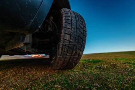 Photo for Car wheel on green grass in mountain valley, bottom wide angle view - Royalty Free Image