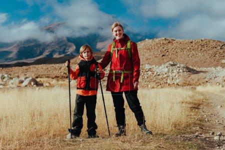 Foto de Feliz joven turista con hijo en las montañas de fondo en otoño - Imagen libre de derechos