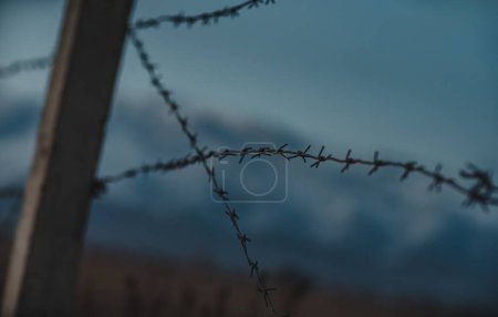 Téléchargez les photos : Clôture en fil de fer barbelé sur fond de montagnes - en image libre de droit