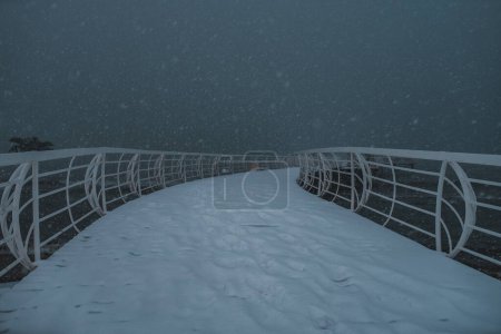 Téléchargez les photos : Jetée enneigée à forte chute de neige au crépuscule - en image libre de droit