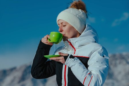 Photo for Young woman tourist drinking tea from a cup on mountains background in winter - Royalty Free Image