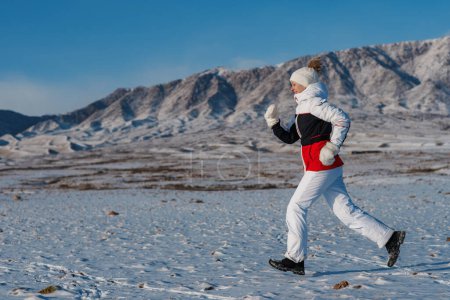 Téléchargez les photos : Sport femme touriste cours sur fond de montagnes en saison d'hiver - en image libre de droit