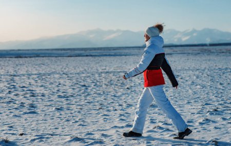 Photo for Sport woman tourist walking in snow on mountains background in winter season - Royalty Free Image