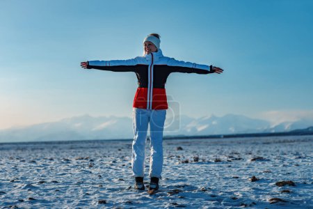 Téléchargez les photos : Femme heureuse touriste étirement vers le haut sur fond de montagnes en saison d'hiver - en image libre de droit
