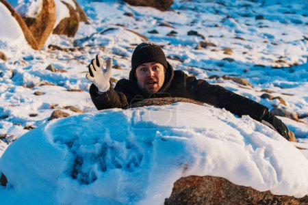 Foto de Joven turista cayendo de la montaña y tratando de subir en invierno - Imagen libre de derechos