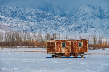 Téléchargez les photos : Vieux chariot rouillé sur fond de montagnes d'hiver - en image libre de droit