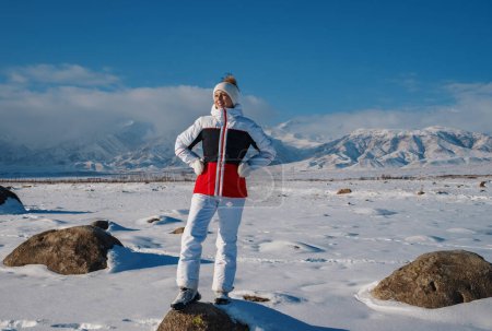 Téléchargez les photos : Jeune femme touriste regarde dans la distance sur fond de montagnes dans la journée d'hiver - en image libre de droit