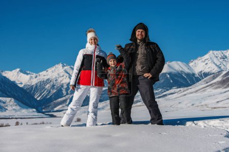Foto de Familia feliz con el niño en las montañas nevadas en invierno - Imagen libre de derechos