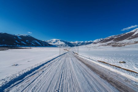 Foto de Camino cubierto de nieve en valle de montaña en invierno - Imagen libre de derechos